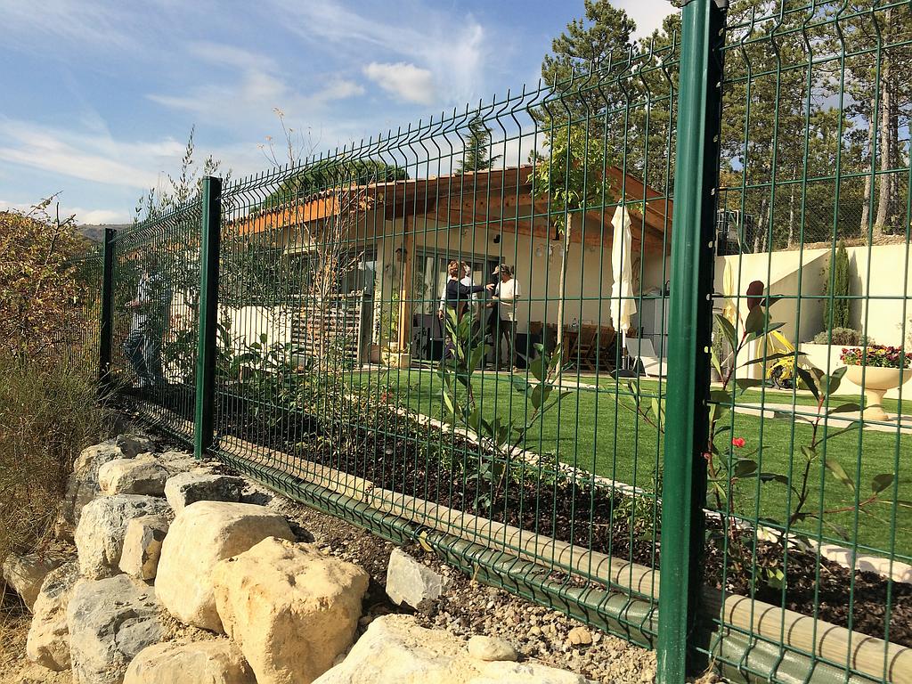 Clôture en panneaux rigides posée au-dessus d’un enrochement